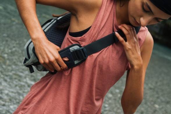 Young woman in sporty, summery hiking clothes with a sporty shoulder bag